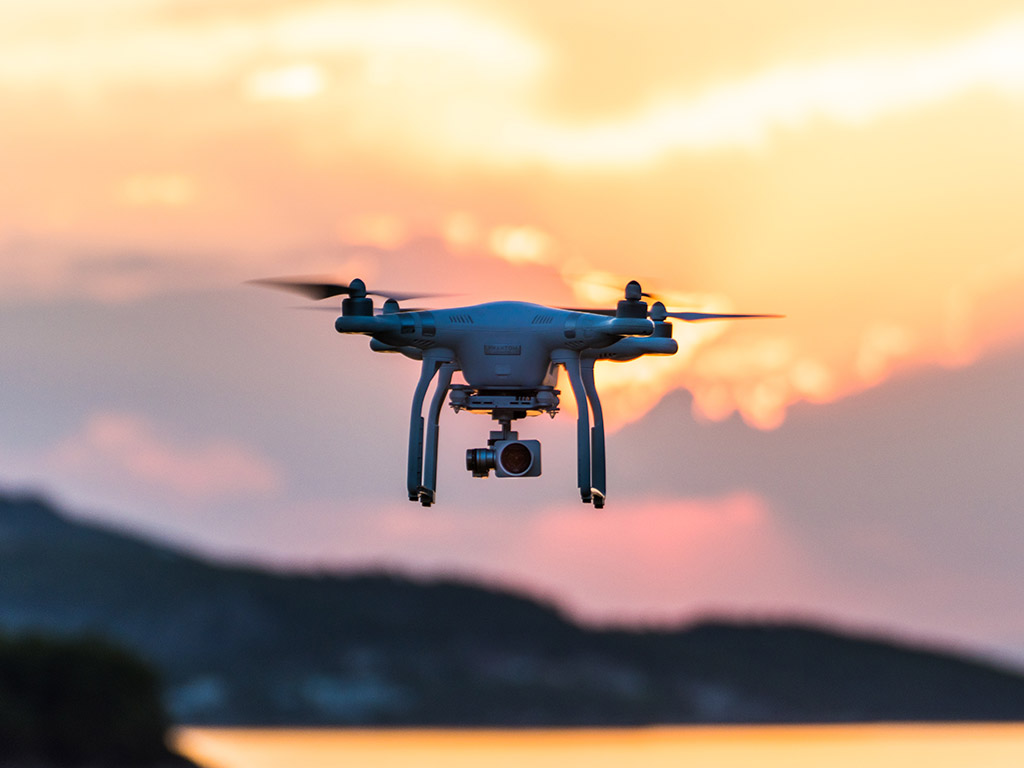 A DJI drone in flight at sunset