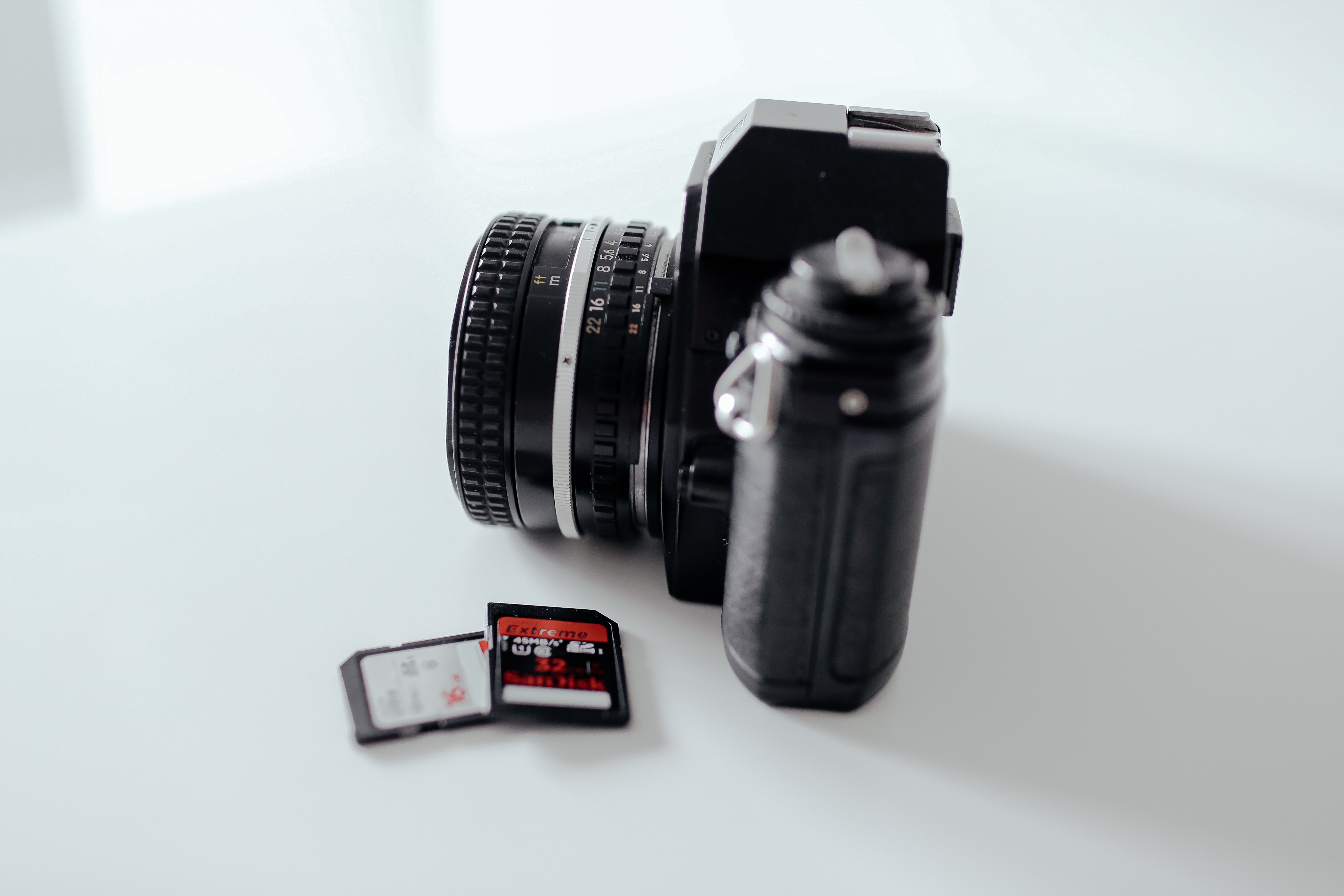 Photo of a camera with some SD cards sitting on a tabel