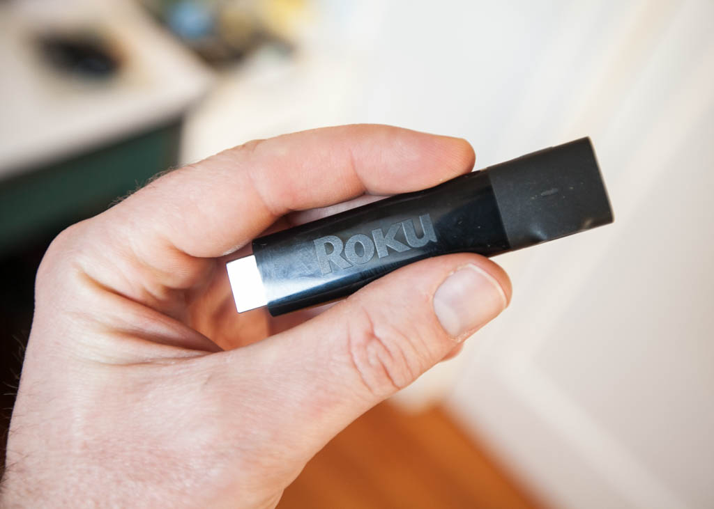 A photo of a hand holding a Roku Streaming Stick+
