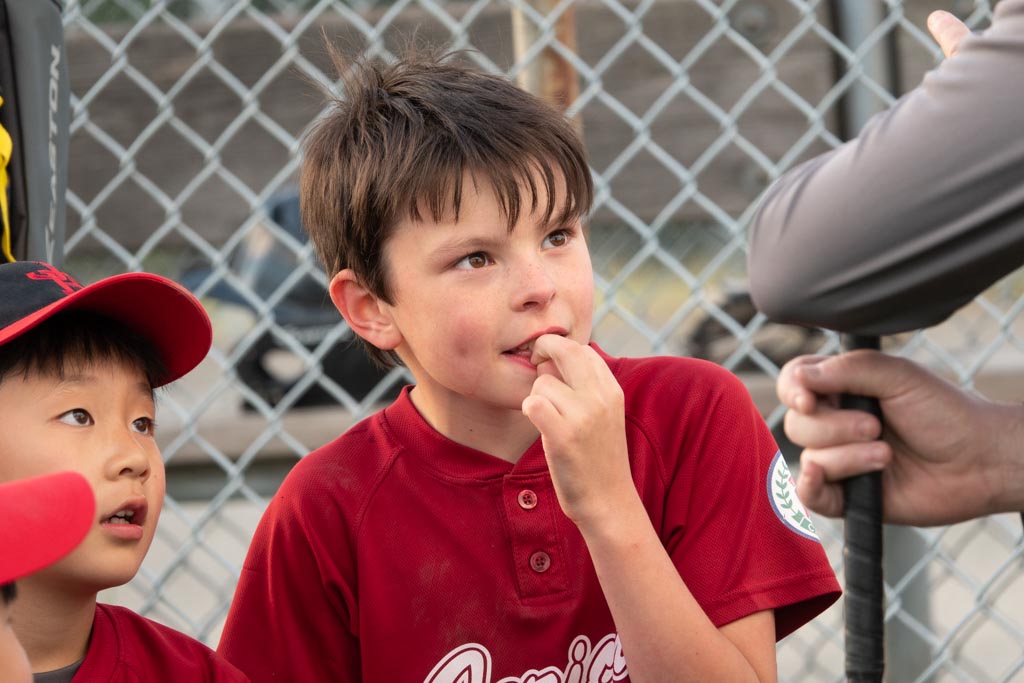 Photo of a boy in baseball uniform listening to his coach taken with the Sony RX10 IV