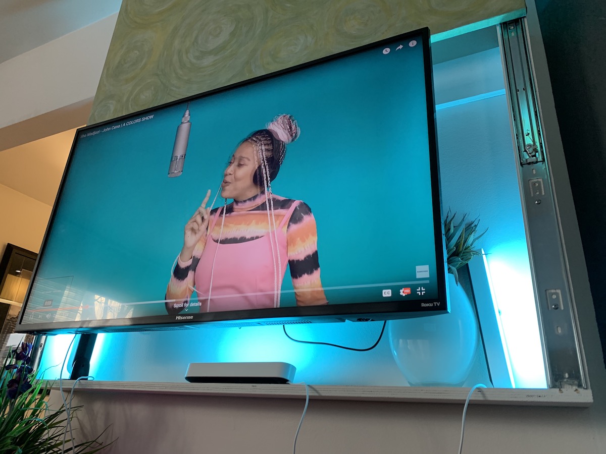 YouTube video still with a young woman singing into a hanging microphone with the Philips Hue Play shining a blue light