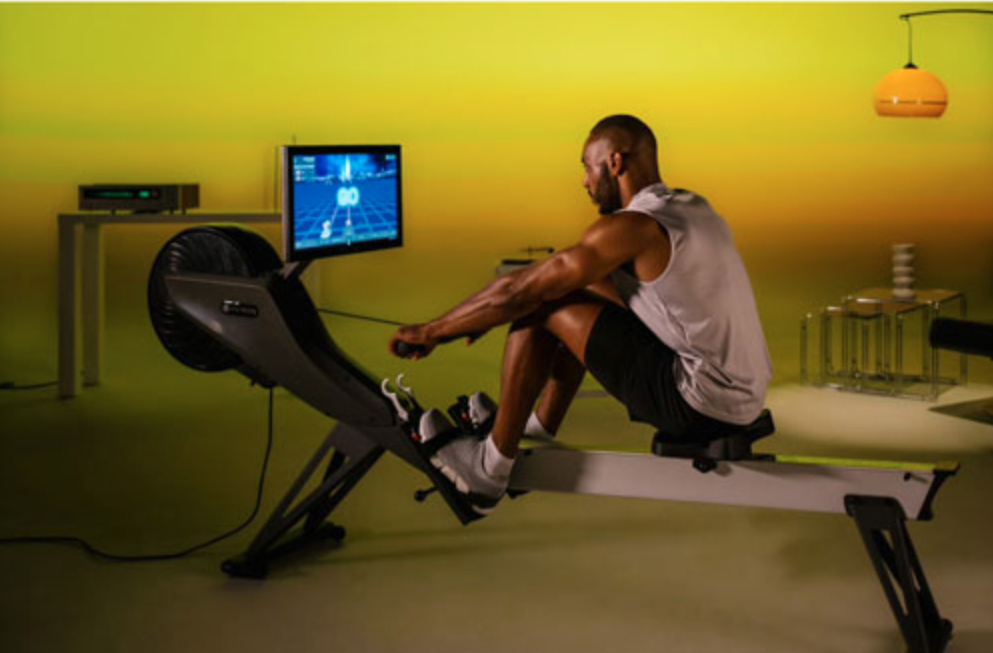 A man rowing and looking at a screen.