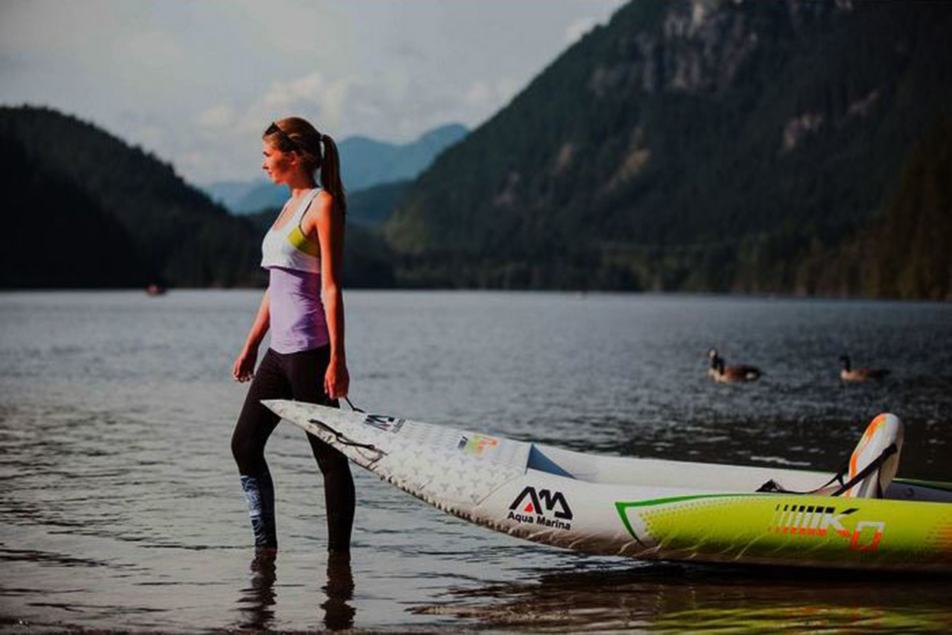 image of a woman standing with a kayak in front of a lake