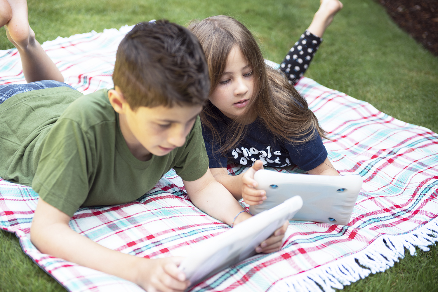 image showing two children on a blanket looking at tablets