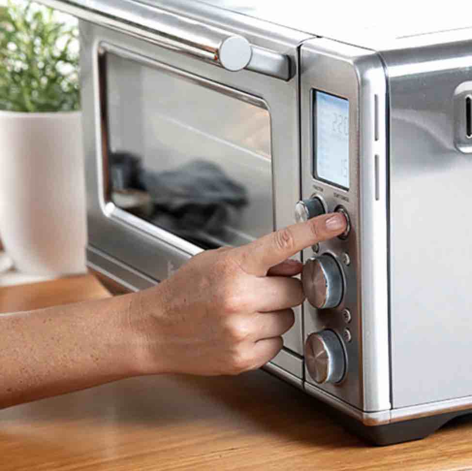 finger pressing a button on a multifunction appliance