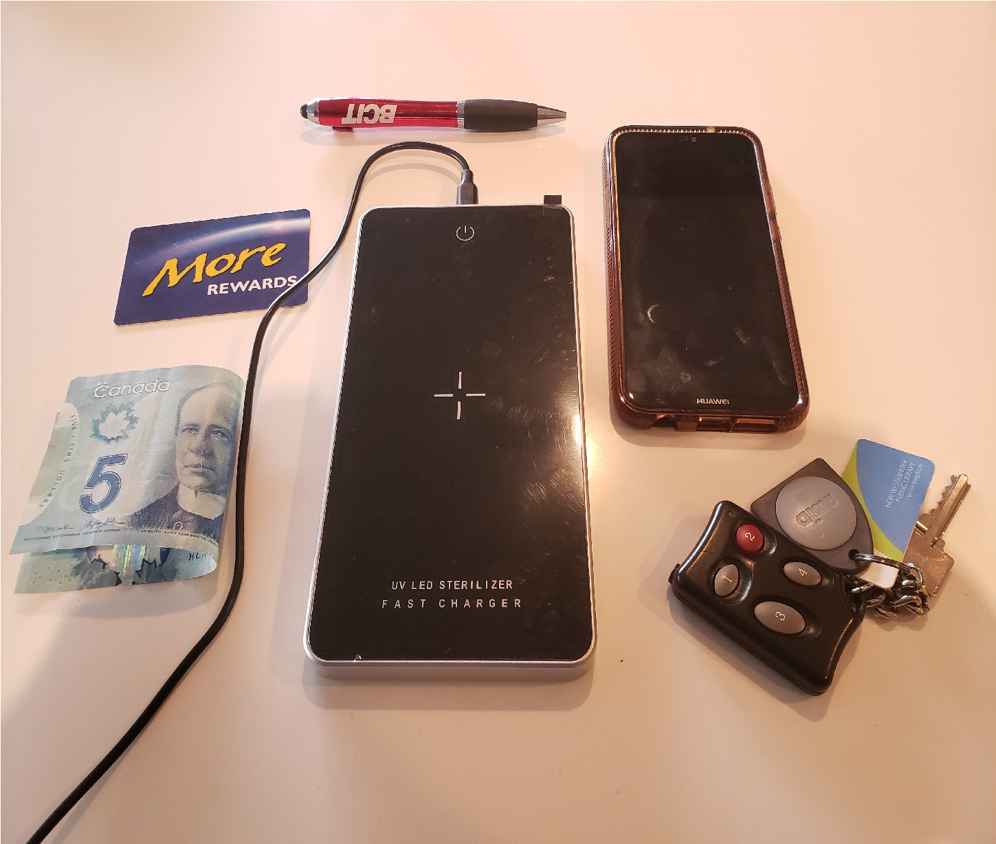 image of the UV sterilizer surrounded by items to sterilize: phone, keys, cash, a card, and a pen