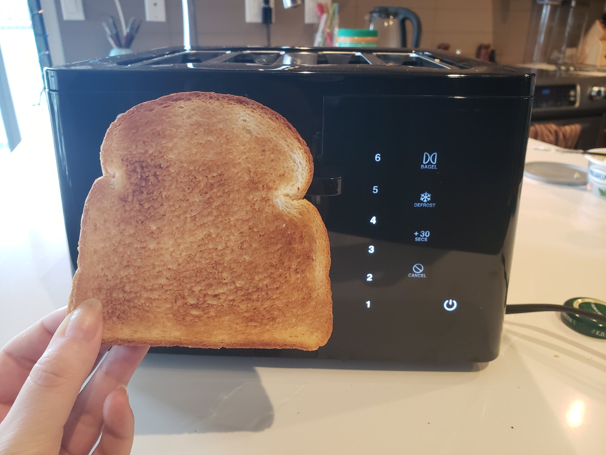 image of a perfectly toasted slice of bread next to the toaster
