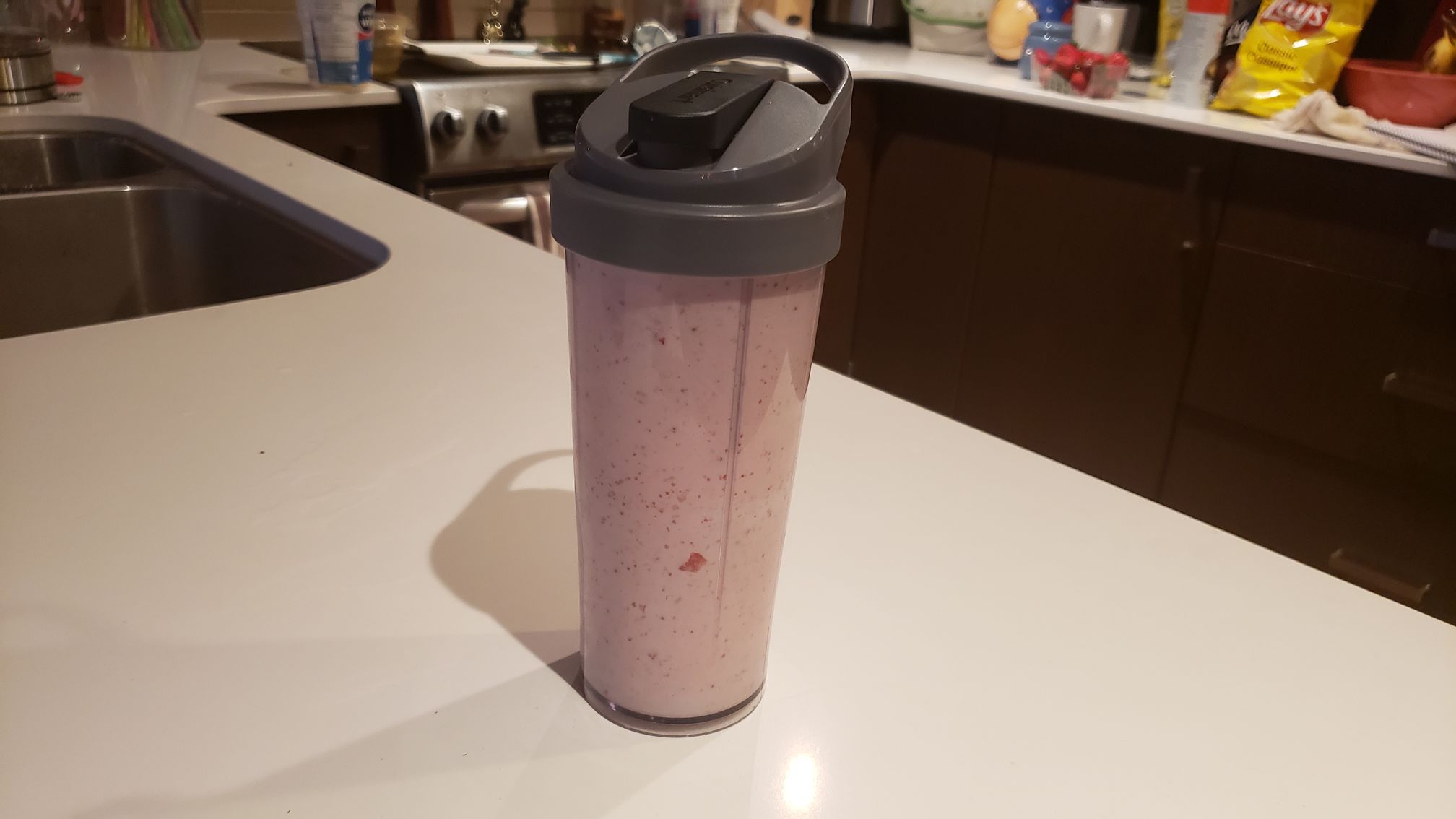 image of the tumbler full of strawberry smoothie with travel lid on