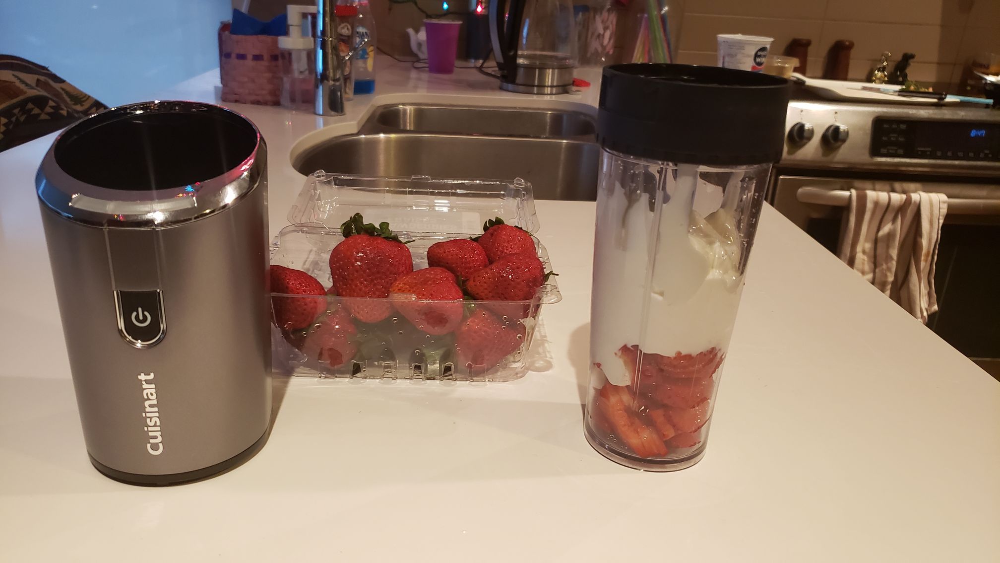 image of blender base next to fresh strawberries and tumbler full of ingredients