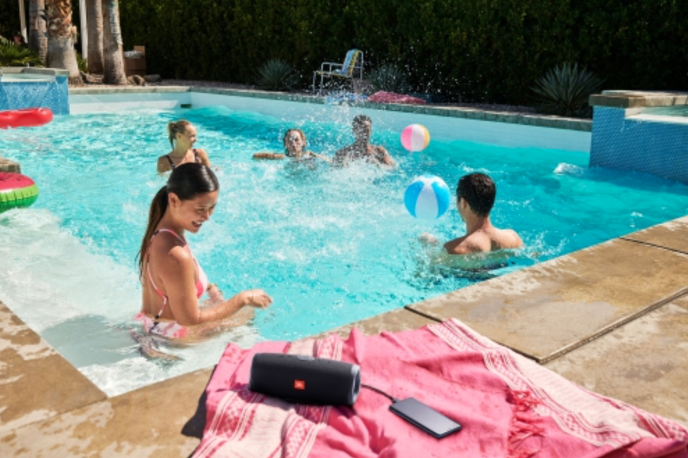 friends hanging at the pool with a JBL portable Bluetooth speaker on the side.
