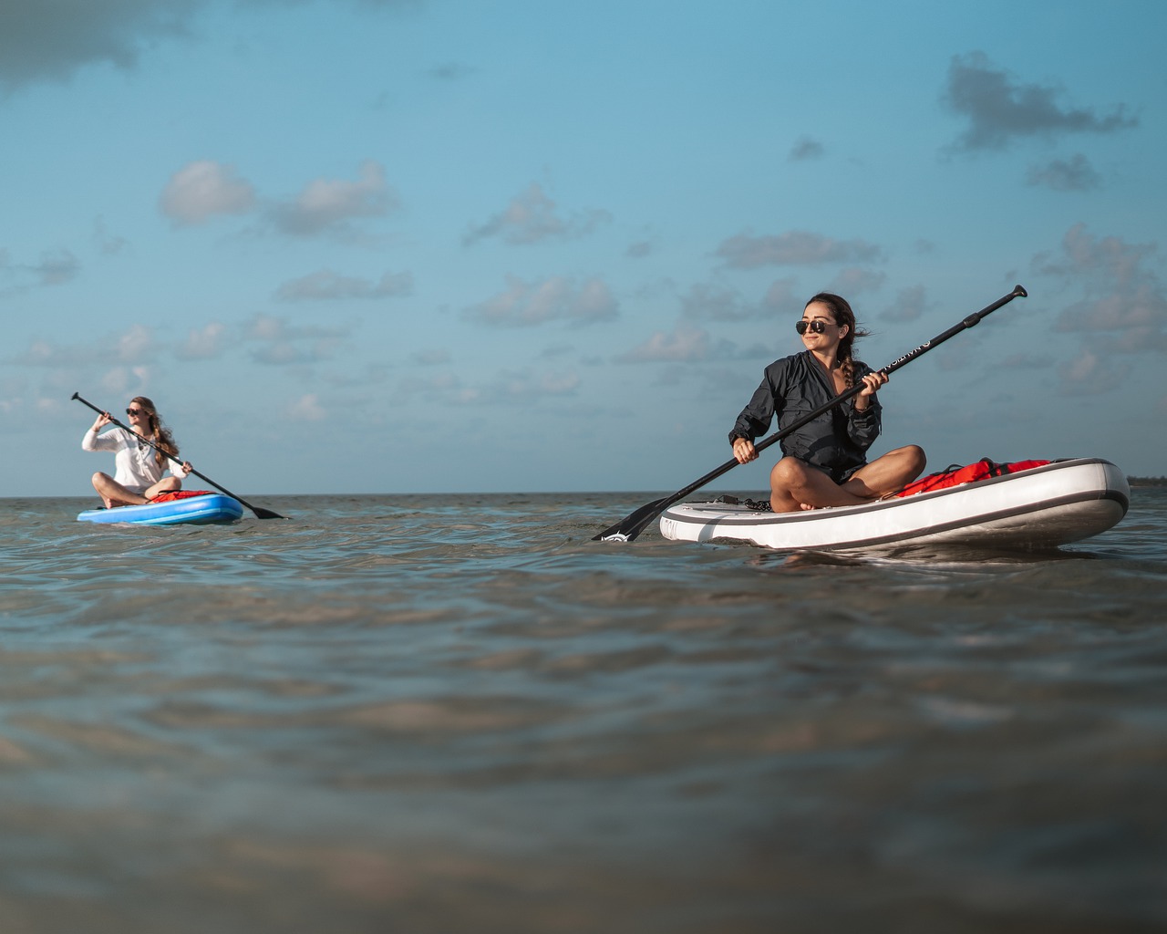 image of 2 women paddle boarding on the ocean