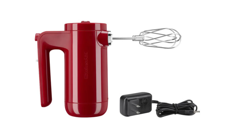 a cordless hand mixer next to its removable charging cable
