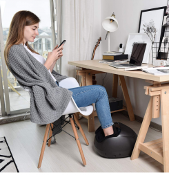 A woman sitting at her desk with a foot massager.