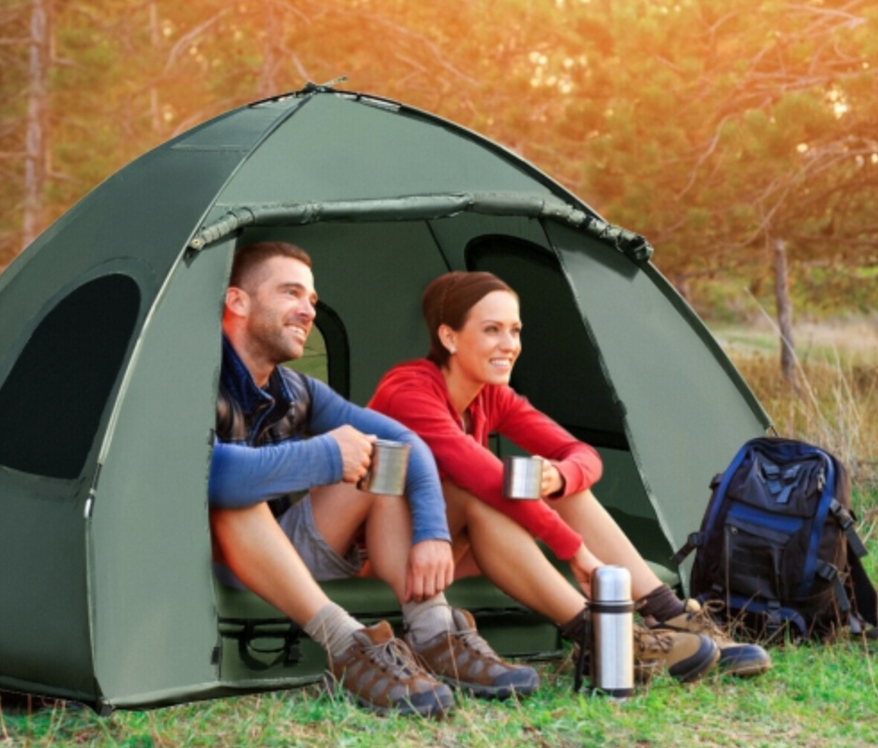 A man and a woman sitting outside of a two-person tent.