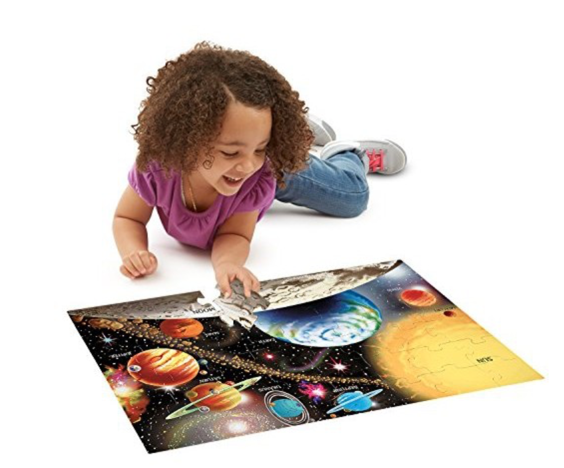 Young girl on the floor with a solar system puzzle.