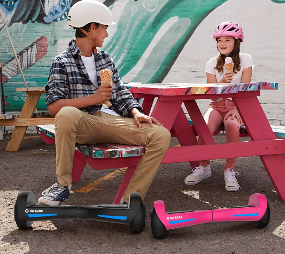A dad and daughter with hoverboards eating ice cream.