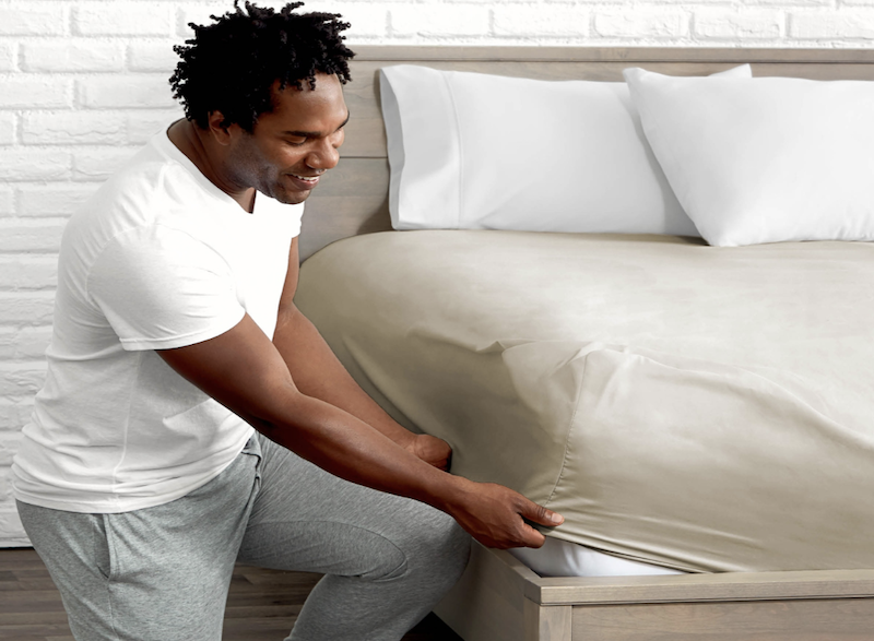 Man putting on fitted sheet.