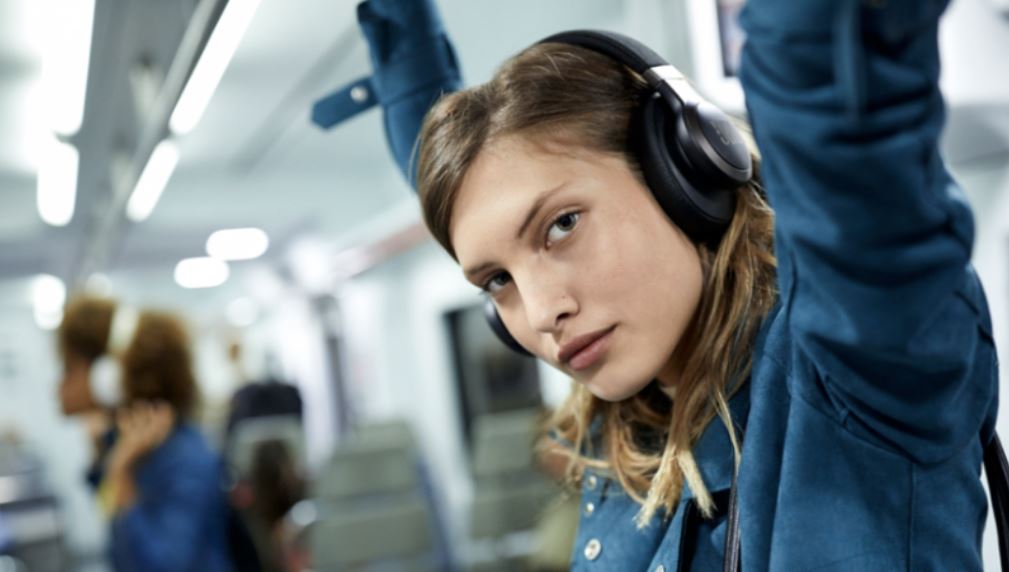 Woman on subway using a pair of over-ear earphones 