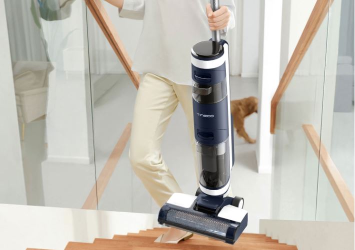 Person carrying wet dry vacuum cleaner up the stairs