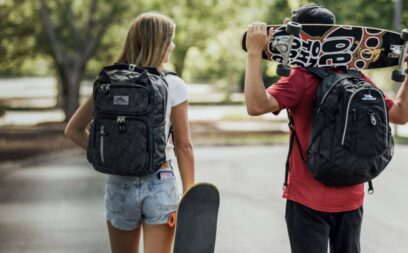 Students walking with backpacks and skateboards.
