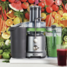 Breville Juice Fountain surrounded by fruits and vegetables in the background.