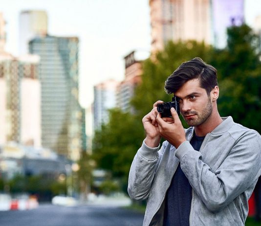 A photo of a photographer in an urban setting shooting with the Sony RX100 VI
