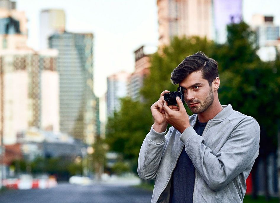 A photo of a photographer in an urban setting shooting with the Sony RX100 VI