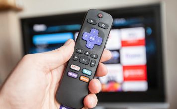 A photo of a hand holding a Roku remote control
