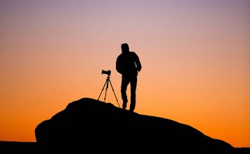 A photo of a photographer using a tripod to shoot a landscape
