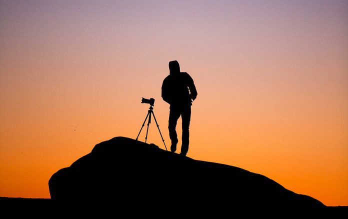 A photo of a photographer using a tripod to shoot a landscape