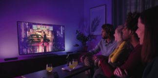 Four friends watching TV with Philips lighting.