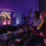 Four friends watching TV with Philips lighting.