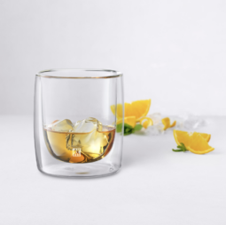 Whiskey tumbler with a drink, ice, and lemon peels