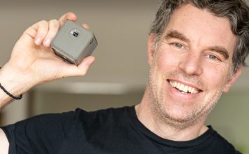 A photo of photographer Justin Morrison holding the XPRIT smart cube projector