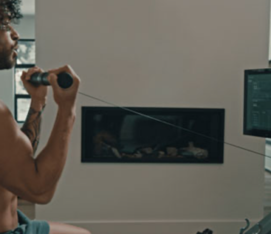Man standing and exercising using a rowing machine