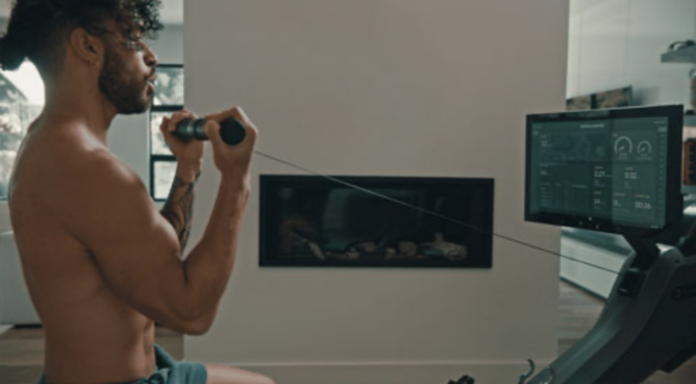 Man standing and exercising using a rowing machine