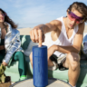 Young people at the beach relaxing with the Ultimate Ears Megaboom 3 outdoor speaker