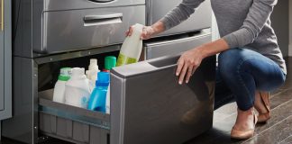 Image of a woman opening a pedestal drawer beneath a washing machine to store cleaning supplies