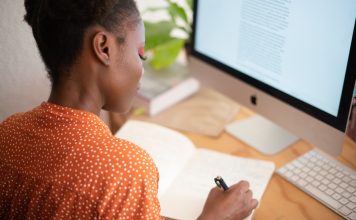 Image of woman working at desk in front of a Mac computer