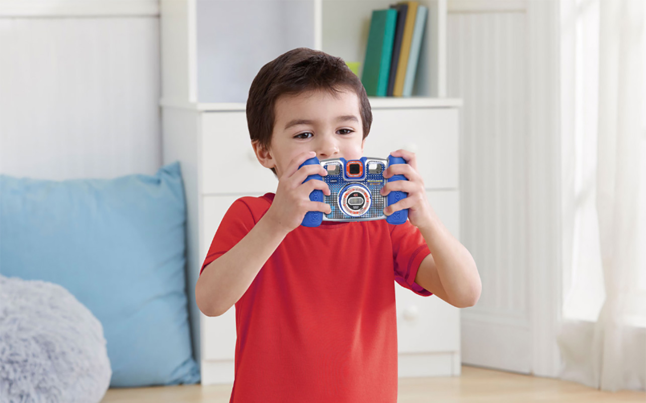 A young boy holding up the VTech Kidizoom camera