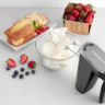 Image of the Cuisinart Cordless Hand Mixer mixing a bowl of cream with fruit and cake nearby