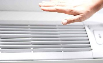 image of a hand feeling cool air from an air conditioner