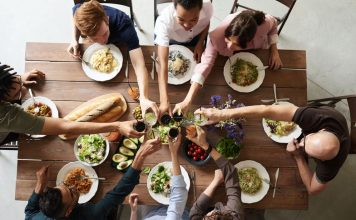 image of a group clinking glasses over a dinner table