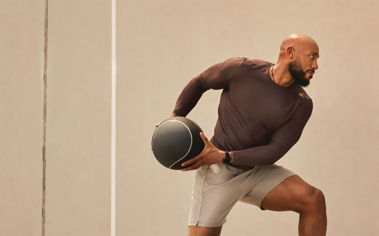 A man holding a baseketball while wearnig the Fitbit Charge 6