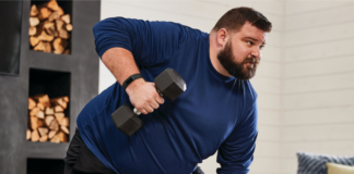 A man lifting weights wearing a Fitbit Charge 5