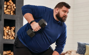 A man lifting weights wearing a Fitbit Charge 5