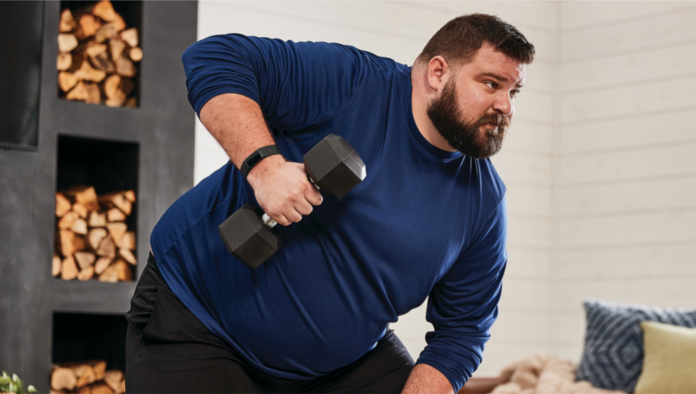 A man lifting weights wearing a Fitbit Charge 5