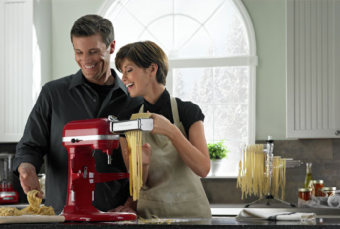couple making pasta using a KitchenAid stand mixer.