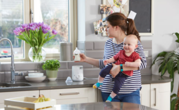 Mother holding a baby and bottle with Tommee Tippee bottle warmer.