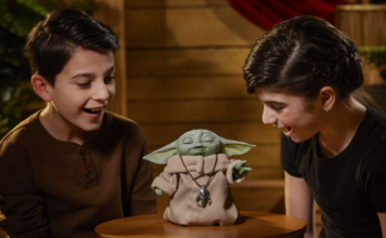 Two kids playing with an animatronic The Child toy.